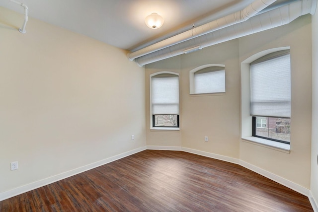 spare room featuring baseboards and dark wood-style flooring