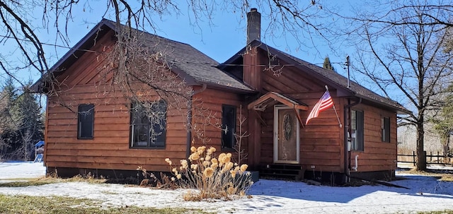 view of front of home featuring entry steps, roof with shingles, and a chimney