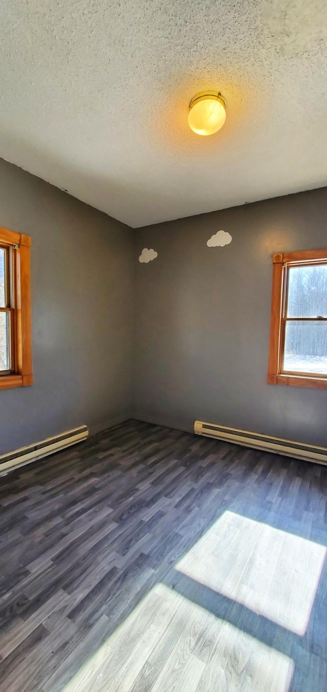 spare room with a baseboard heating unit, a baseboard radiator, dark wood finished floors, and a textured ceiling