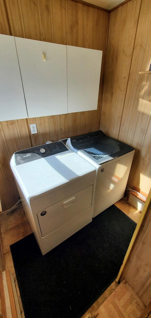 laundry area with wooden walls, cabinet space, and washer and dryer