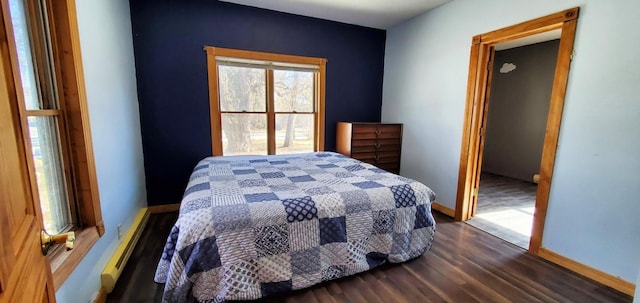 bedroom featuring baseboards, a baseboard heating unit, and dark wood-style flooring