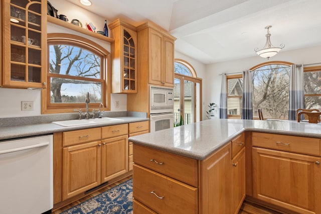 kitchen featuring white appliances, glass insert cabinets, pendant lighting, and a sink