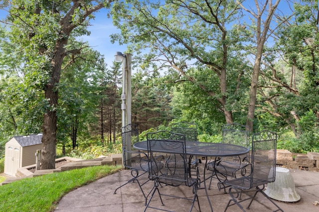 view of patio / terrace with a storage shed, outdoor dining space, and an outdoor structure