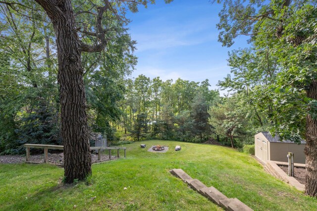 view of yard with a storage shed, an outdoor fire pit, and an outdoor structure