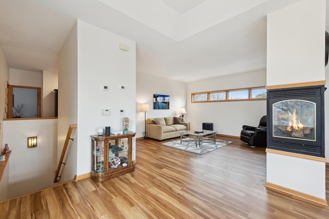 living area with light wood finished floors, a multi sided fireplace, and baseboards