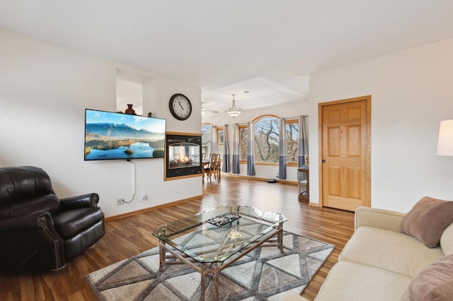 living area featuring baseboards, a multi sided fireplace, and wood finished floors