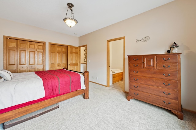 bedroom featuring light colored carpet, connected bathroom, baseboards, and two closets