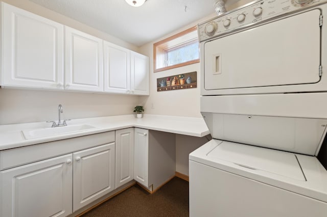 laundry area featuring stacked washer / dryer, a sink, and cabinet space