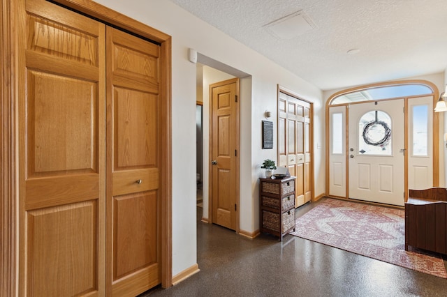 foyer entrance with baseboards and a textured ceiling