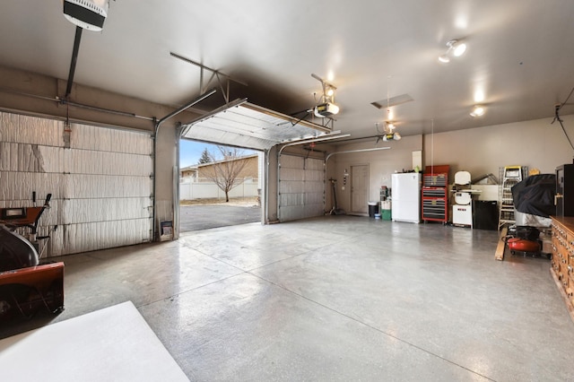 garage with a garage door opener and freestanding refrigerator