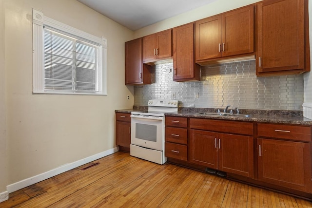 kitchen with a sink, baseboards, light wood-style floors, white range with electric stovetop, and dark countertops