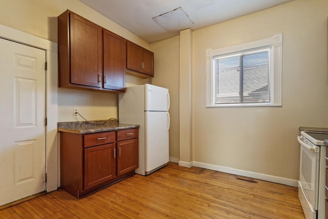 kitchen with white appliances, dark countertops, light wood-style flooring, and baseboards