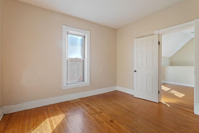 spare room with baseboards and hardwood / wood-style flooring