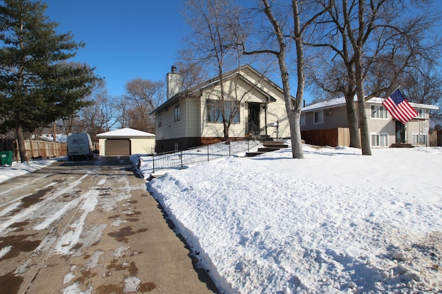 view of front facade featuring a garage, an outdoor structure, fence, driveway, and a chimney