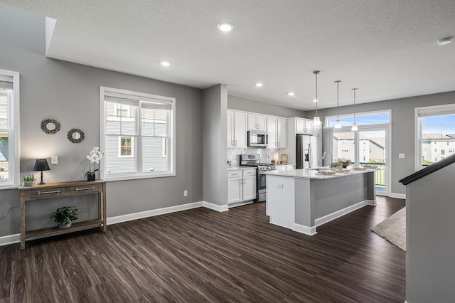 3485 109th Ln NE, Blaine, MN 55449 - kitchen featuring stainless steel appliances, dark wood finished floors, baseboards, a center island with sink, and a textured ceiling