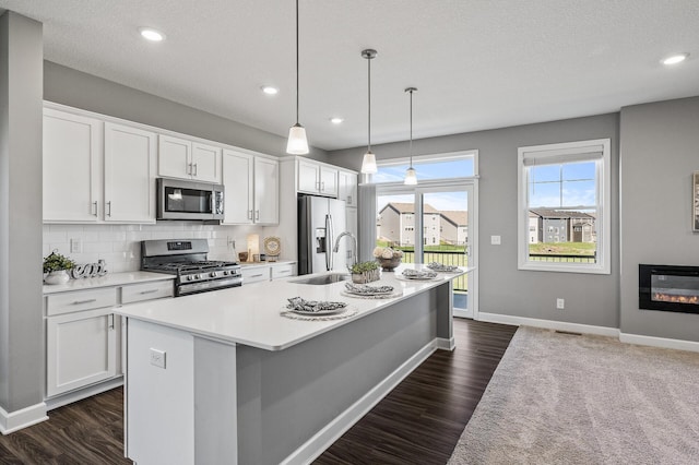 3485 109th Ln NE, Blaine, MN 55449 - kitchen with appliances with stainless steel finishes, an island with sink, a sink, light countertops, and white cabinetry