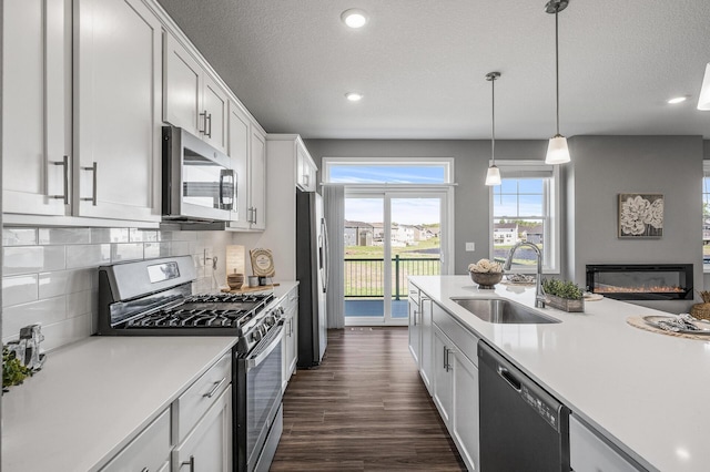 3485 109th Ln NE, Blaine, MN 55449 - kitchen featuring a sink, appliances with stainless steel finishes, light countertops, a glass covered fireplace, and dark wood-type flooring