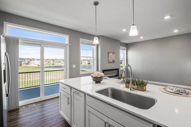 3485 109th Ln NE, Blaine, MN 55449 - kitchen with a sink, a glass covered fireplace, light countertops, recessed lighting, and decorative light fixtures