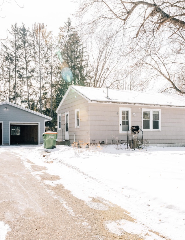 snow covered rear of property with an outbuilding and a detached garage