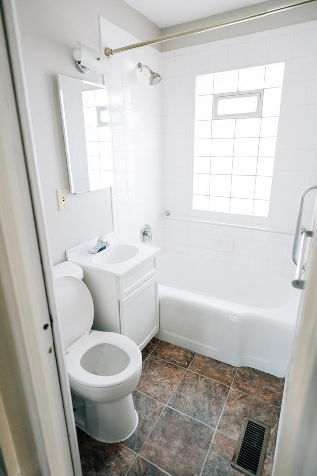 bathroom featuring vanity, visible vents, stone finish floor, shower / bathing tub combination, and toilet