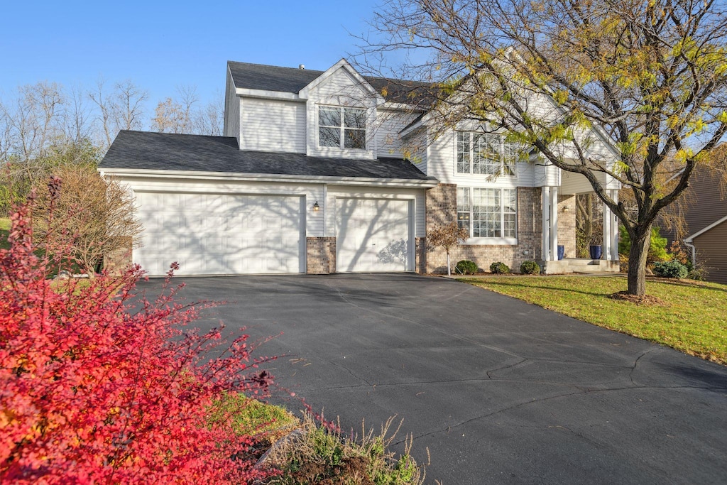 view of front facade featuring driveway, an attached garage, a front lawn, and brick siding