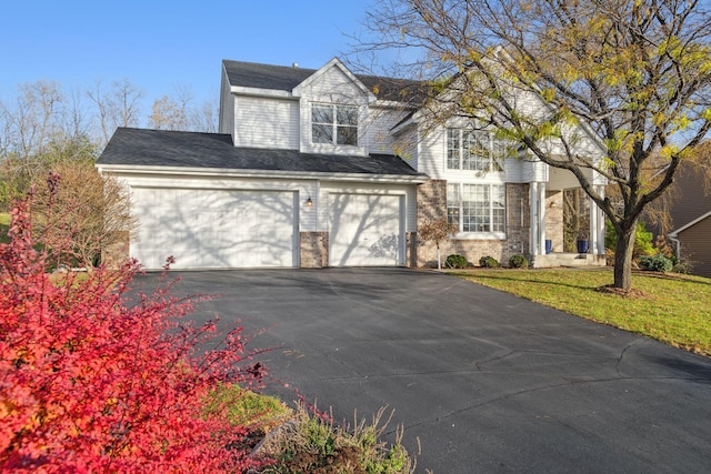 view of front facade featuring driveway, an attached garage, a front lawn, and brick siding