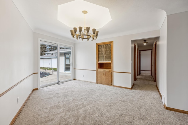 carpeted empty room featuring an inviting chandelier and baseboards