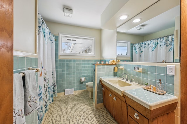 full bath featuring tile patterned flooring, toilet, visible vents, vanity, and tile walls