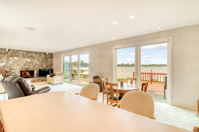 dining room featuring light carpet, a stone fireplace, and recessed lighting