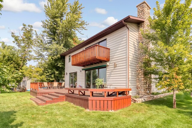 back of property featuring a yard, a chimney, and a balcony