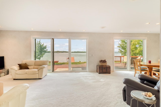 living room featuring a wealth of natural light, carpet flooring, a water view, and recessed lighting