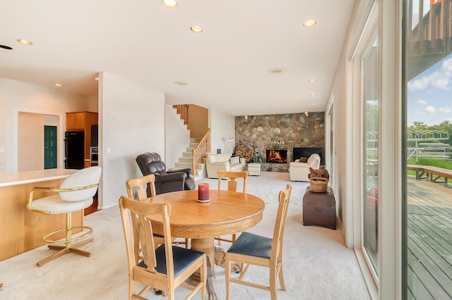 dining room featuring recessed lighting, light carpet, a fireplace, and stairs