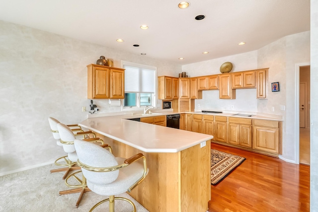 kitchen featuring recessed lighting, a peninsula, light wood-style floors, light countertops, and black appliances