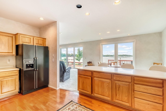 kitchen with light wood finished floors, light countertops, black fridge, and recessed lighting