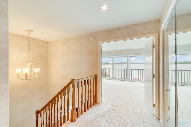 corridor featuring carpet flooring, plenty of natural light, an upstairs landing, and an inviting chandelier