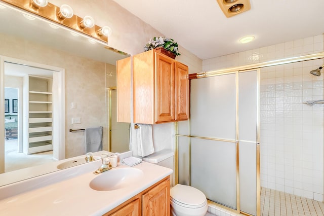 bathroom with tiled shower, vanity, and toilet