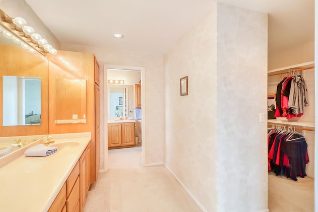 bathroom with a spacious closet, baseboards, and vanity