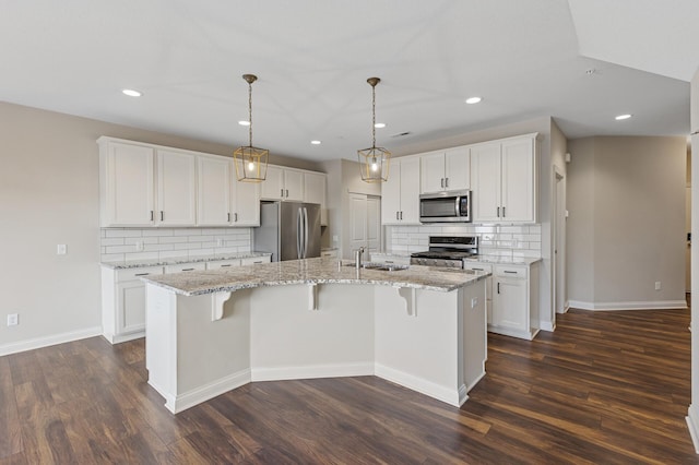 kitchen with a center island with sink, appliances with stainless steel finishes, dark wood-style flooring, white cabinetry, and a sink