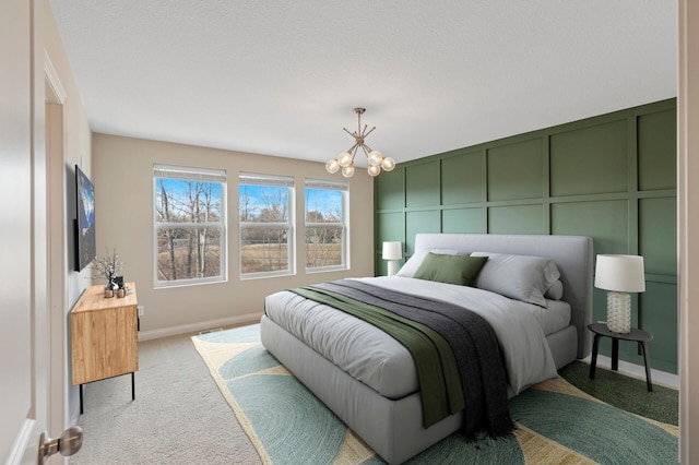 bedroom with a chandelier, carpet, a decorative wall, and baseboards