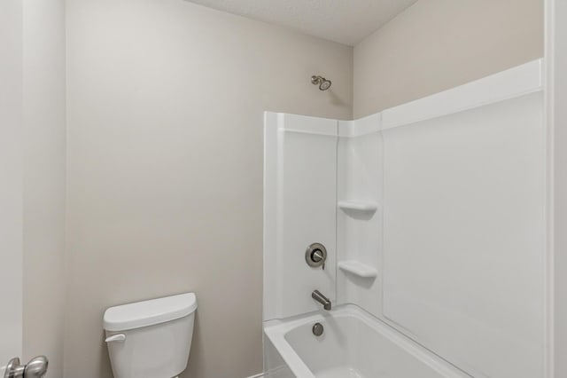 bathroom featuring toilet, shower / tub combination, and a textured ceiling