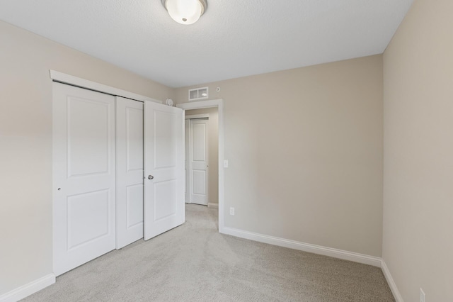 unfurnished bedroom featuring light colored carpet, a closet, visible vents, and baseboards