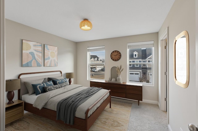 bedroom with light carpet, multiple windows, and baseboards