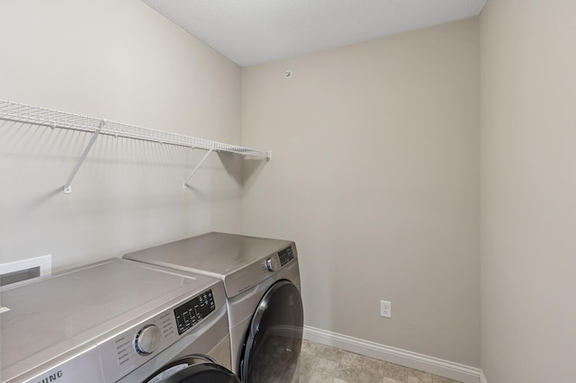 laundry area with laundry area, washer and clothes dryer, and baseboards