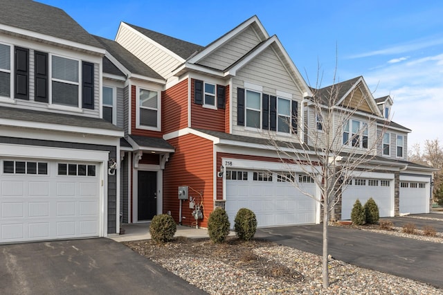 townhome / multi-family property with driveway, a garage, and roof with shingles