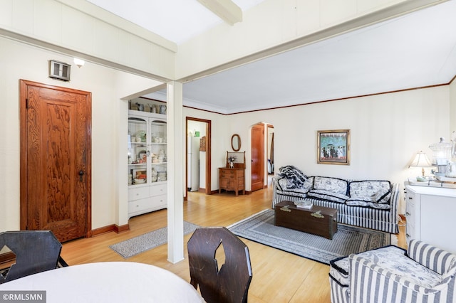 living room with arched walkways, beam ceiling, crown molding, wood finished floors, and baseboards