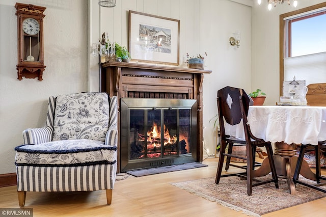 sitting room with a glass covered fireplace and wood finished floors