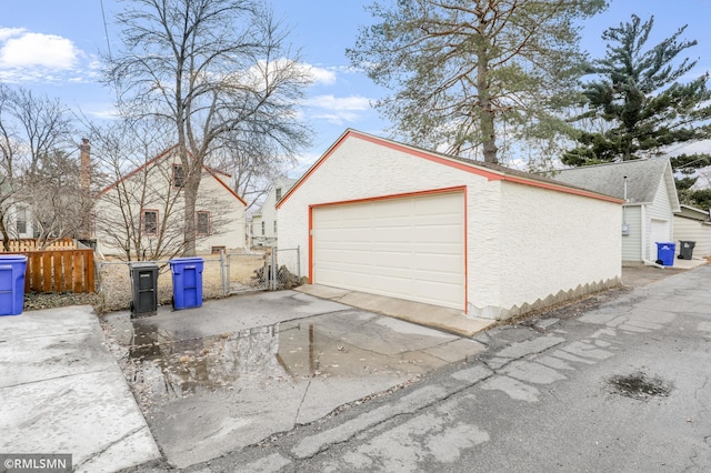 detached garage with concrete driveway, fence, and a gate