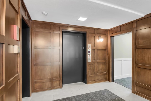 interior space with light tile patterned floors, a decorative wall, and elevator