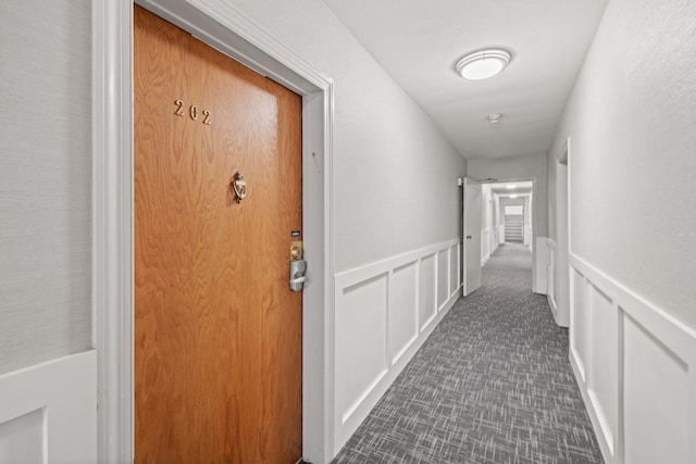 hall featuring a wainscoted wall and a decorative wall