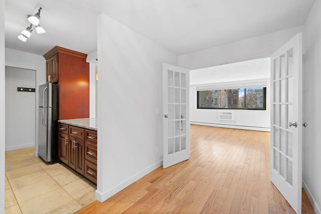 hall featuring a baseboard heating unit, french doors, light wood-type flooring, and baseboards